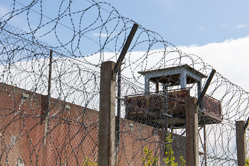 Prison with old guard tower and rolls of barbed wire on a fence barrier