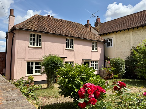 Writtle, UK - July 12, 2023: A pretty pink cottage with roses in the front garden in the village of Writtle, Essex, UK.
