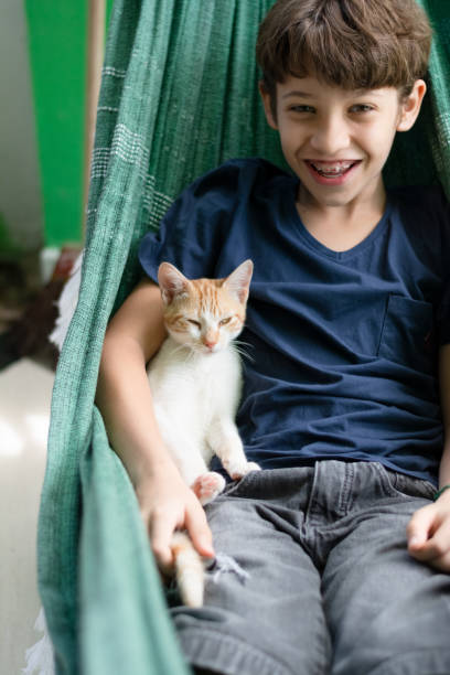 istock Boy inside a hammock with his pet cat petting him. Love for animals. 1627919779