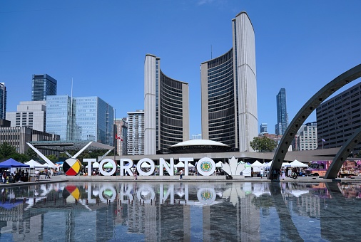 Toronto, Canada - August 31, 2022: View to CN Tower and some skyscraper at Toronto downtown. Many pedestrians are around.