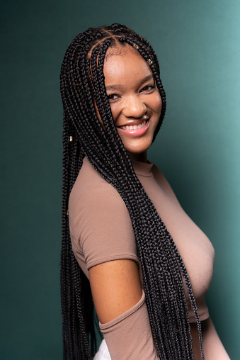 Portrait of young, beautiful black model with long braided hair. Isolated on dark cyan background.