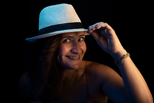 Portrait beautiful woman, mature, holding hat. Beautiful and happy person. Isolated on black background.