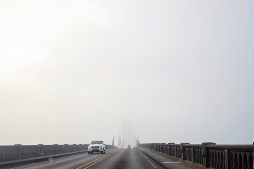 Newport, Oregon, USA - August 9, 2023.  Cars travel along the Aquina bay bridge on a very foggy summer day.