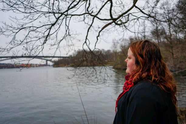 istock Side view of woman looking away while standing by river during winter 1628001016