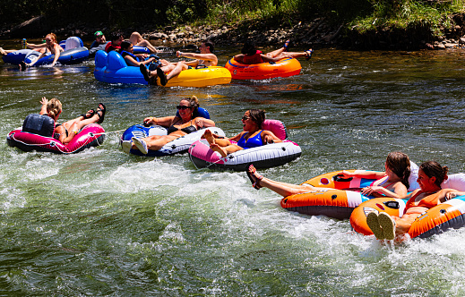 Golden, Colorado, USA, August 12, 2023, Several happy females in colorful river tubes  in whitewater floating down  Clear Creek