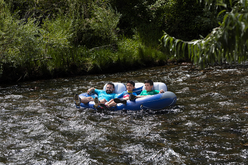 Golden, Colorado, USA, August 12, 2023 Father and two young sons floating swiftly down Clear Creek in single blue river tube