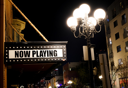 “Now Playing” sign up in a marquee opposing a bright lamp post in Nashville, Tennessee