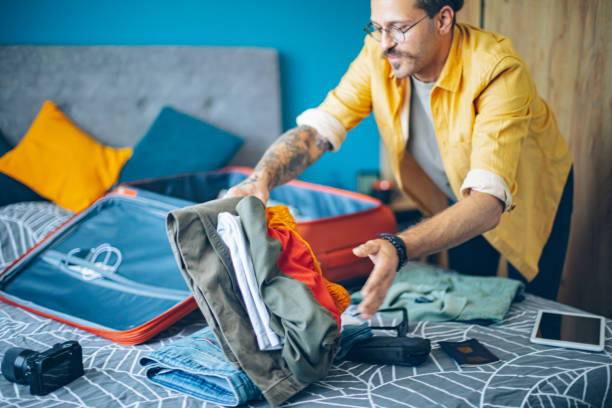 istock Man packing his suitcase in his bedroom, getting ready for travel 1628072688