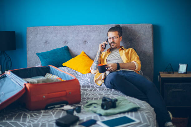 istock Man is packing his suitcase and talking on a mobile phone 1628083619