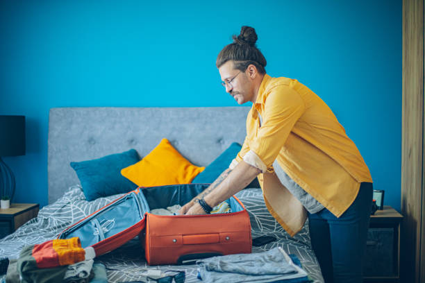 istock Man packing his suitcase in his bedroom, getting ready for travel 1628093617