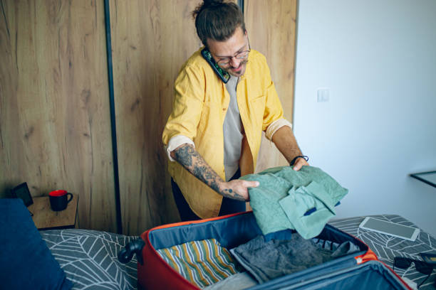 istock Man is packing his suitcase and talking on a mobile phone 1628096317