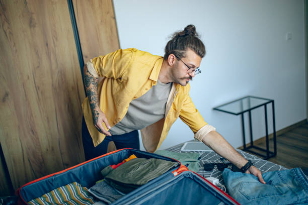 istock Man packing his suitcase in his bedroom, getting ready for travel 1628103774