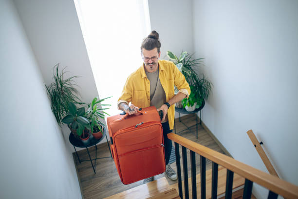 istock Man carrying his luggage up a staircase 1628104688