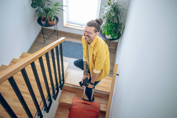 istock Man carrying his luggage up a staircase 1628106859