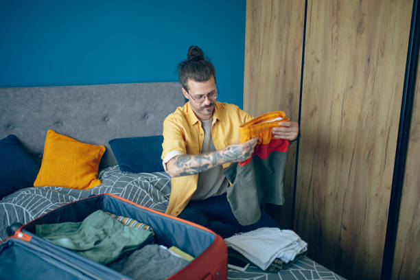 istock Man packing his suitcase in his bedroom, getting ready for travel 1628112220