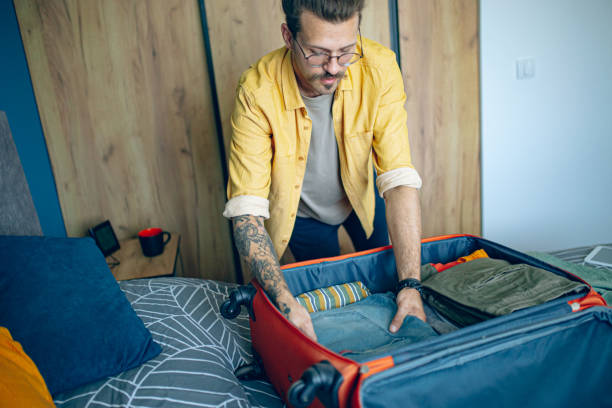 istock Man packing his suitcase in his bedroom, getting ready for travel 1628114357