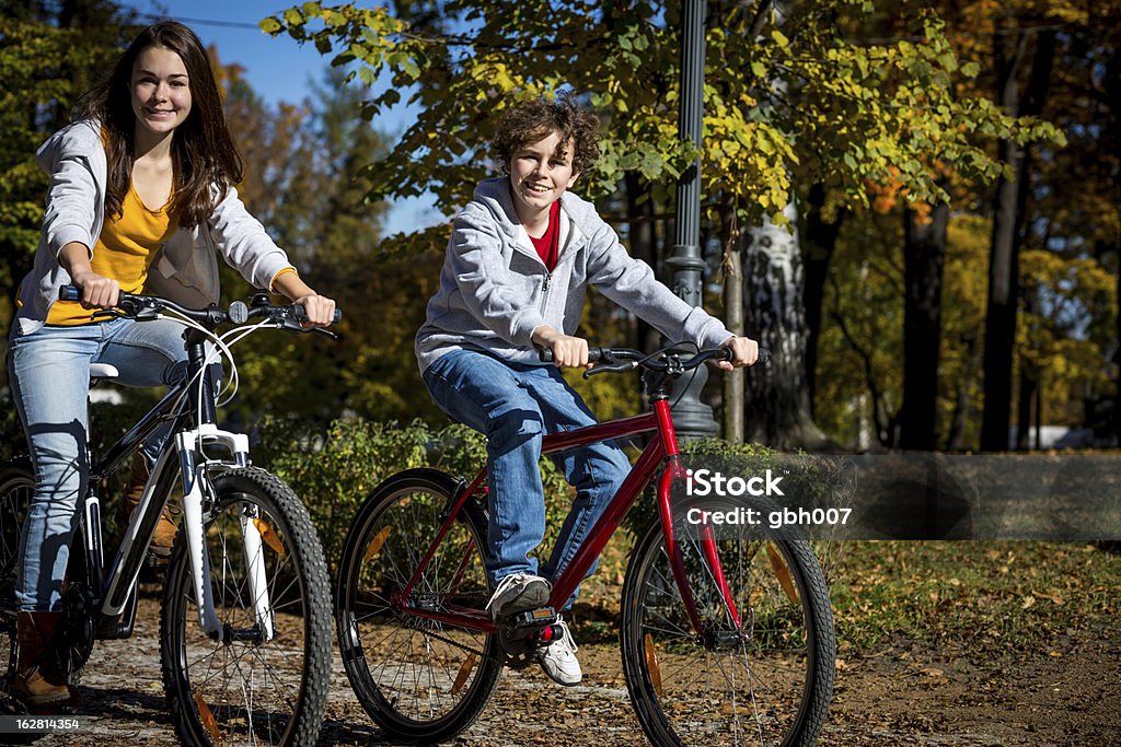 Miejski biking- dziewczynka i chłopiec konna rowery w mieście park - Zbiór zdjęć royalty-free (14-15 lat)