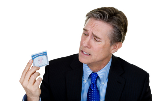 Man wearing a suit with a concerned expression holding a social security card 