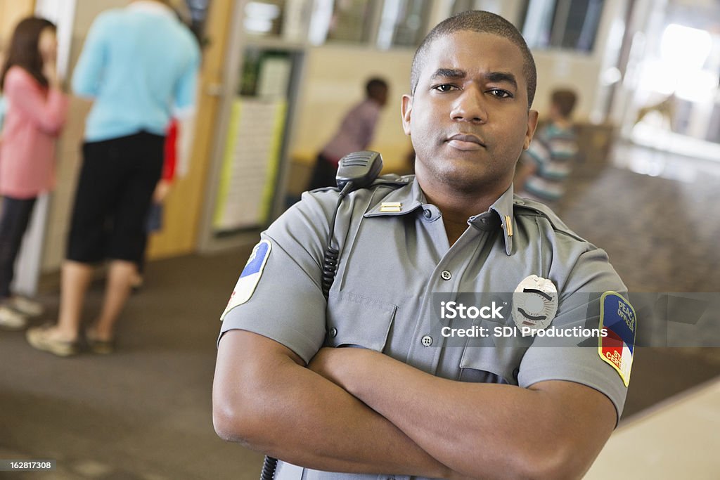 Policial patrolling corredor na escola primária - Foto de stock de Guarda de segurança royalty-free