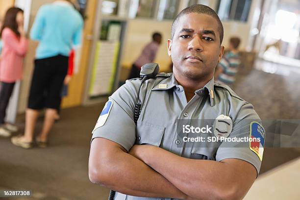 Foto de Policial Patrolling Corredor Na Escola Primária e mais fotos de stock de Guarda de segurança - Guarda de segurança, Ofício de Segurança, Campus