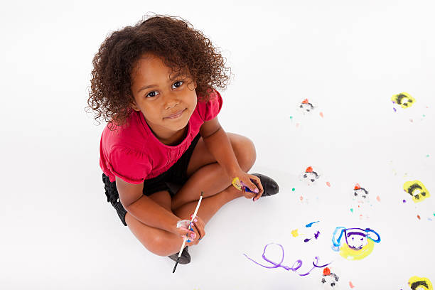 ragazza asiatica africana po'di pittura sul pavimento. - preschooler preschool child painting foto e immagini stock