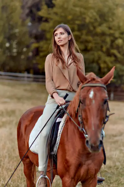 Woman and horse in rural landscape. Equestrianism promotes well-being and stress relief. The portrait captures equestrian training, showcasing an athlete's farm and outdoor saddle sports arena.