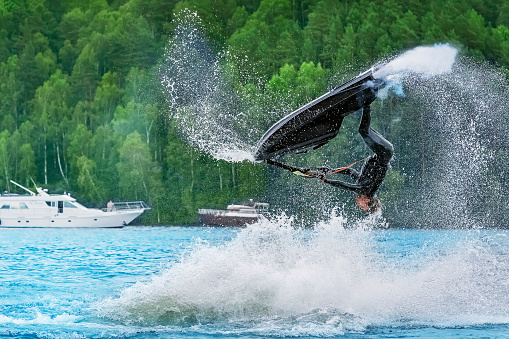 Freestyle Jet Skier performing back flip creating at lot of spray. Russia, Irkutsk, August 5, 2023