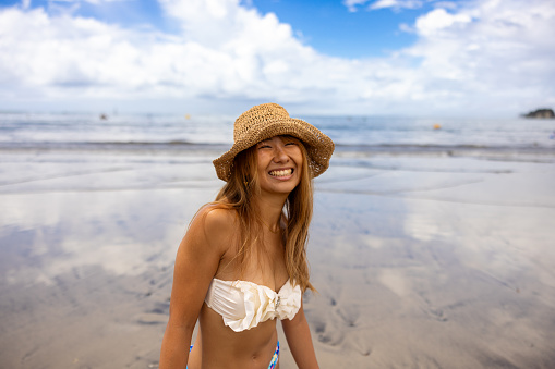 Portrait of happy woman in bikini standing on summer beach