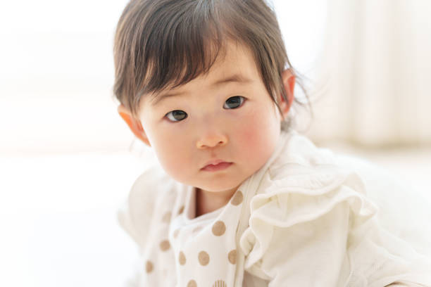 asian baby sitting floor looking at  the camera