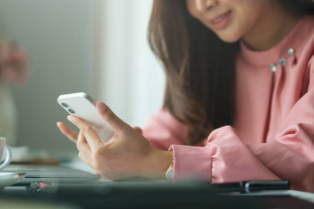istock Serious female employee using mobile phone at office desk. 1628283015