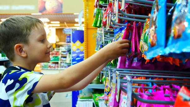 Close-up of many colorful packages of gummies in a supermarket and a boy taking one stock photo