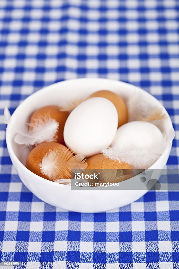 Huevos, feathers en un tazón sobre fondo mantel - Foto de stock de Alimento libre de derechos