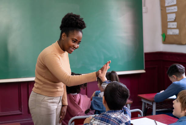 istock Happy black teacher celebrating a students accomplishment with a high five during class 1628347681
