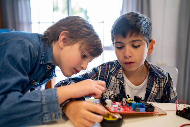 istock Caucasian school kids working together on a project during a robotics class connecting wires to a circuit board 1628348231