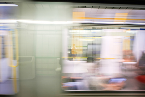 Blurred motion of passengers waiting at station and riding on fully automated self-driving light rapid transit train passing through station.  Vancouver, British Columbia, Canada.