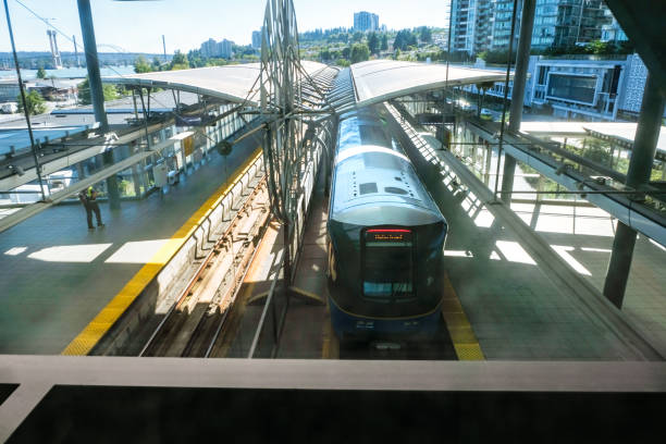 A fully automated self-driving light rapid transit train stopped at an above ground station.  Greater Vancouver skyline in background.  British Columbia, Canada.