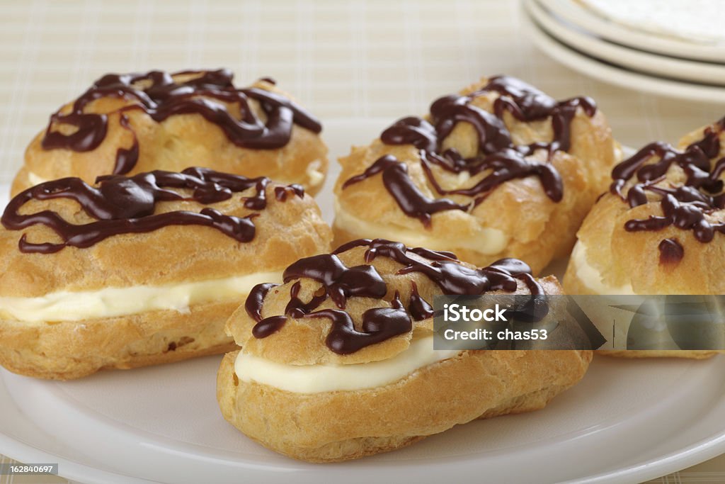 Chocolate Eclairs Chocolate eclairs with cream filling on a platter Baked Pastry Item Stock Photo