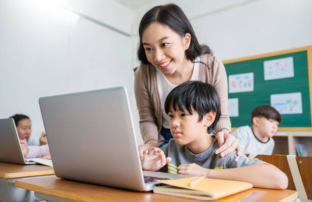 istock Pupil boy, teacher learn computer in classroom at elementary school. Student boy studying primary school. Children coding online in classroom. Education knowledge, successful teamwork concept banner 1628467399