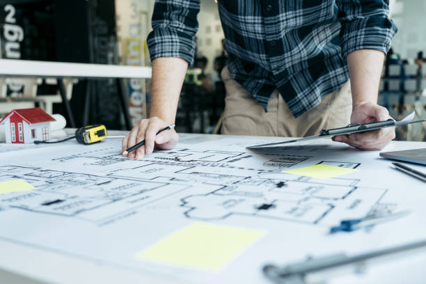 istock Interior designer or architect reviewing blueprints and holding pencil drawing on desk at home office. 1628483852