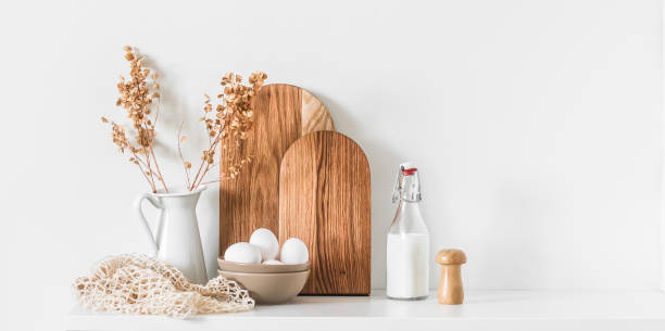istock Cozy scandinavian kitchen interior background - dishes cutting boards,  bowl with eggs, a jug of dried flowers on a white table 1628530452