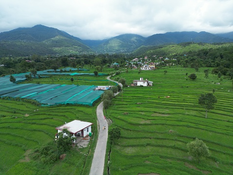 An aerial of a landscape with lush, green fields, and homes with mountainscapes in the background