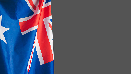 A Close-up of the Australian flag is on the left side on a gray background with copy space for text