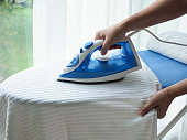 Woman hands ironing cloth on the ironing board at home - Household work concept