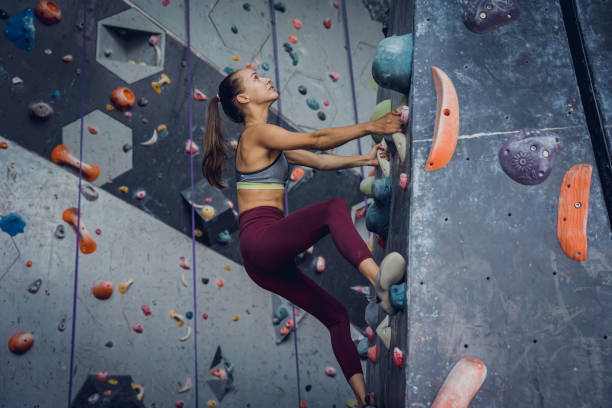 istock A strong female climber climbs an artificial wall with colorful grips and ropes. 1628665543