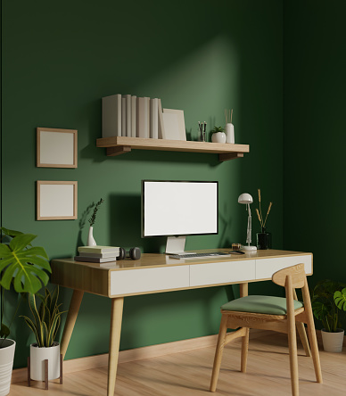 Modern trendy home office interior with a computer white screen mockup on a minimal wooden table against the green wall, a chair, a wall shelf with decor, and indoor plants. 3d render, 3d illustration