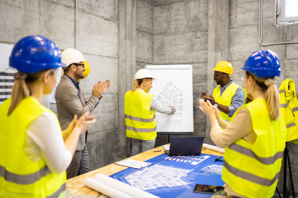 istock Motivated and positive group of structural engineers at construction site meeting laughing and clapping hands. 1628709118
