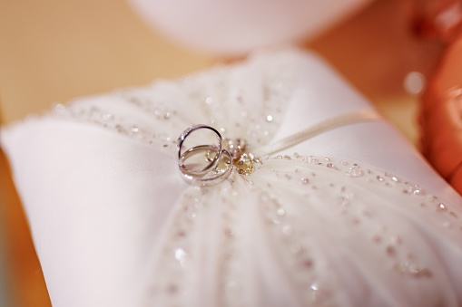 Close-up shot of wedding rings on a silk pillow