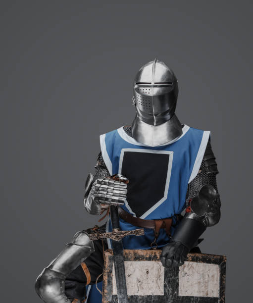istock Medieval knight in blue surcoat holding a sword and shield 1628730155