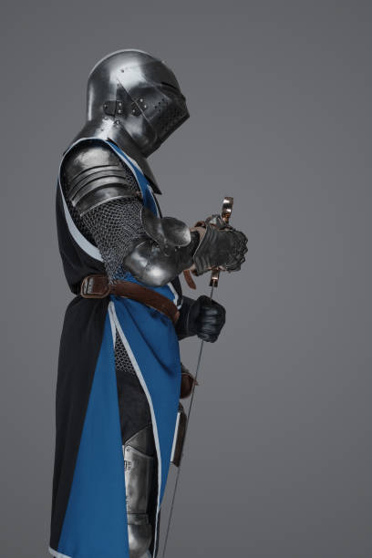 istock Medieval guard dressed in armor and blue surcoat holding a sword 1628731242