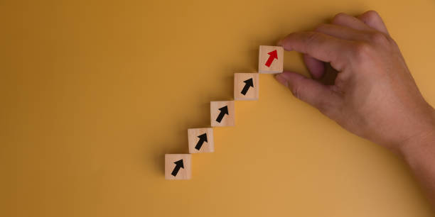 istock Hand holding wood cube icon arrow up growth performance success development management on yellow background. 1628747373